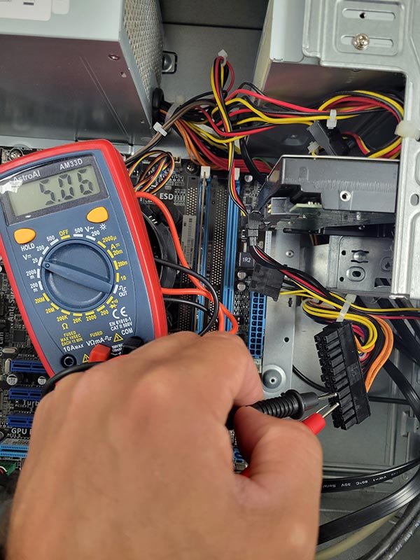 computer repair technician testing a power supply with a multimeter